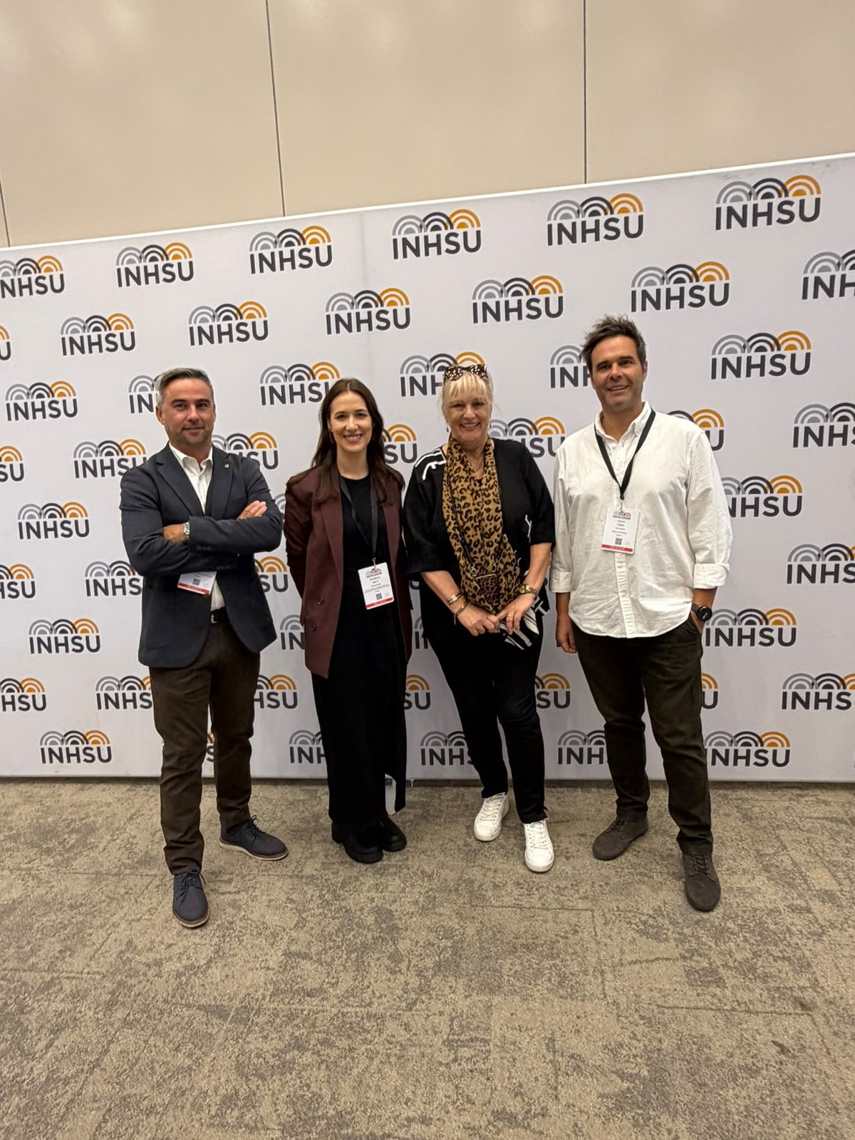 Four delegates at the INHSU 2026 conference backdrop